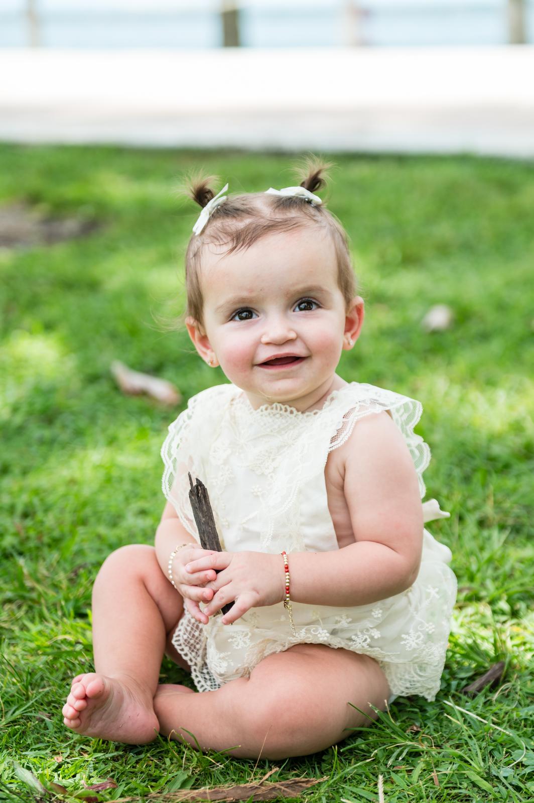 Nava Dayan sitting on the grass in a lace dress
